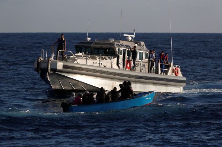 Migrants on a wooden boat are rescued by a patrol vessel of the Tunisia Navy