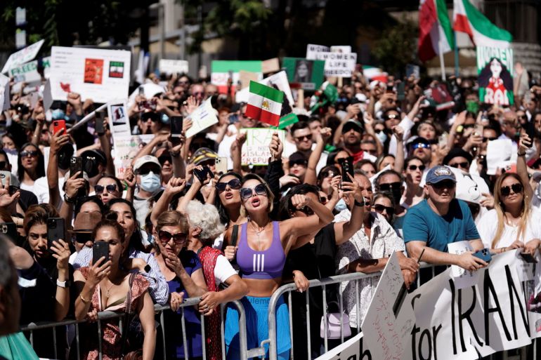 People hold up Iranian flags and signs at a rally in Los Angeles