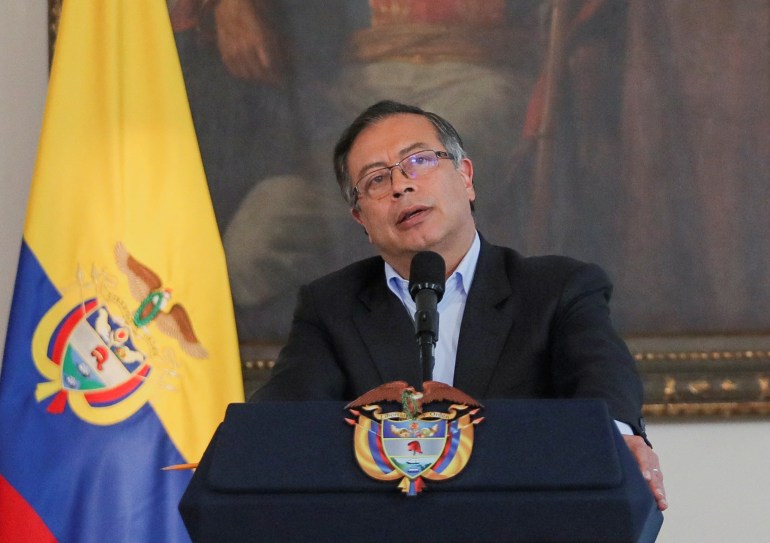 Gustavo Petro speaks at a podium in front of a painting and a Colombian flag