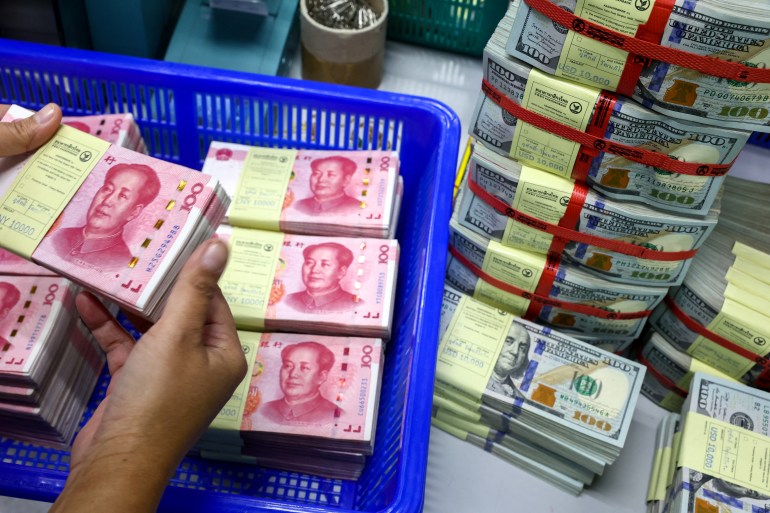 A bank employee count China’s renminbi (RMB) or yuan notes next to U.S. dollar notes at a Kasikornbank in Bangkok, Thailand, January 26, 2023. REUTERS/Athit Perawongmetha