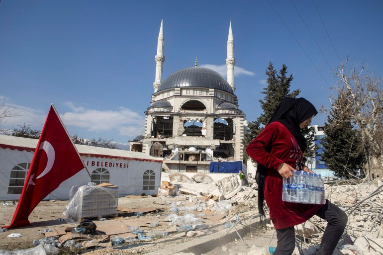 A girl carries a box of water bottles next to a damaged mosque in the aftermath of a deadly earthquake in Antakya, Turkey February 16, 2023. REUTERS/Nir Elias TPX IMAGES OF THE DAY