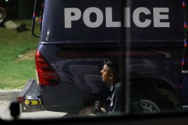 A police officer takes position near a police vehicle after an attack on a police station in Karachi