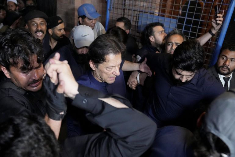 Pakistan's former Prime Minister, Imran Khan, along with his supporters walks as he leaves the district High Court in Lahore, Pakistan