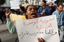 A woman carries a banner, which reads: "Feminist, Tunisian, African. We are all men and women immigrants", during a protest after Tunisian President Kais Saied ordered security forces to stop all illegal migration and expel all undocumented migrants, in Tunis, Tunisia February 25, 2023.