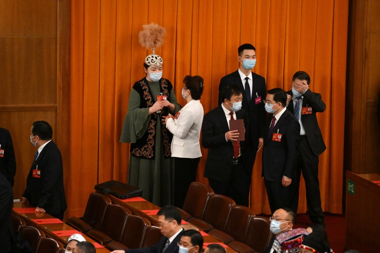 Delegates milling about including one in a traditional outfit of one of China's ethnic groups. The others are all wearing suits