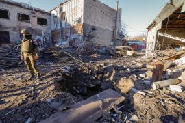 An investigator stands next to a crater in the site of recent shelling
