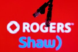 Ethernet cables are seen in front of the logos of Canadian telecoms companies Rogers and Shaw