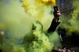 A protester is lost in a haze as they hold up a canister spewing smoke in Nantes, France.