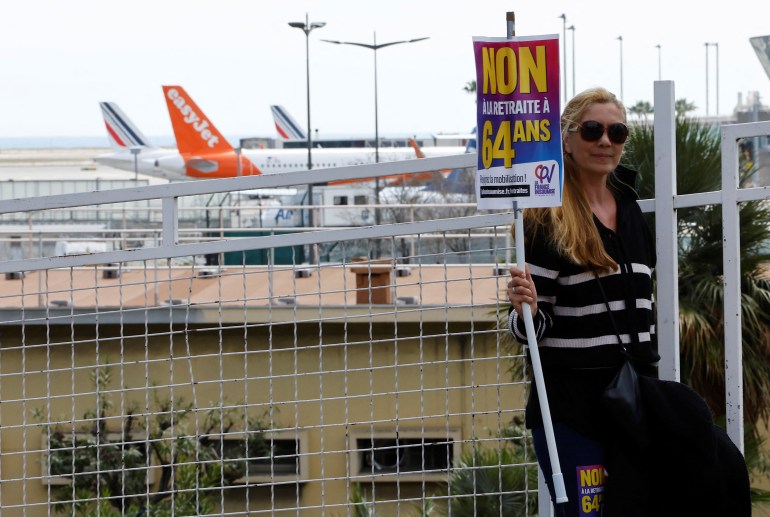 A protester, holding a placard which reads "No to 49.3", a special clause in the French Constitution, to push the pensions reform bill through the National Assembly without a vote by lawmakers, attends a demontration to block Nice international airport 