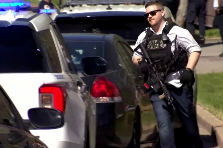 A law enforcement officer, weapon in hand, runs near the Covenant School after a shooting in Nashville, Tennessee.