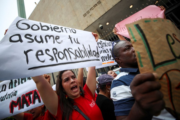Demonstrators hold posters as they take part in a protest following the death of migrants at a Mexican detention centre