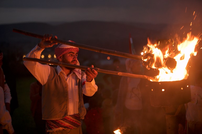 A man lights a fire with a torch in his hand