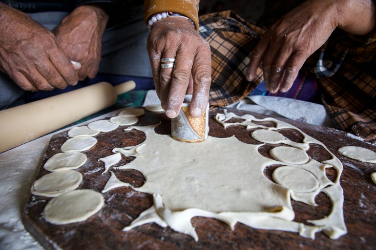Fateem's hands cut out small circles of dough using an Arabic coffee cup