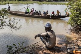 Artisanal gold miners cross The Gambia river at the Bantakokouta gold mine