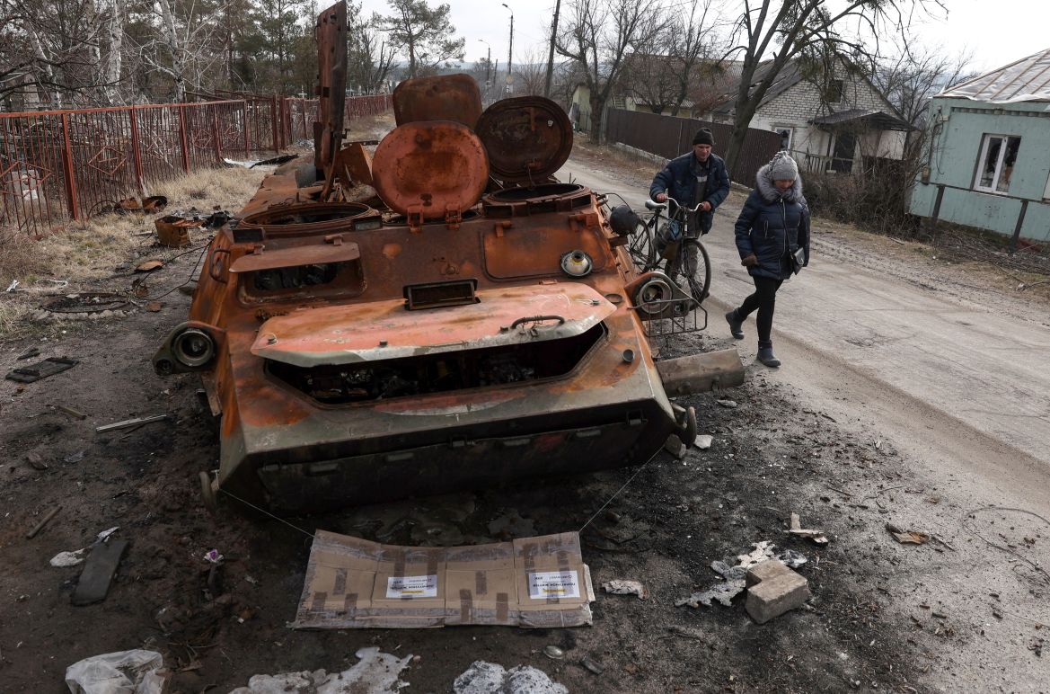 Local residents walk past destroyed APC (armored personnel carier) in the town of Svyatogirsk, Donetsk region