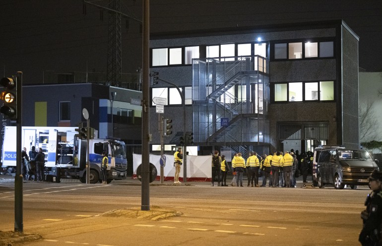 Police around the Jehovah's Witness building in Hamburg, The building is modern and three storeys high. The lights are all on.