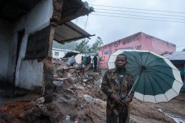 A resident stands with an umbrella in the Chimwankhunda location in Blantyre on March 14, 2023 following heavy rains caused by cyclone Freddy. - The death toll from Cyclone Freddy in Malawi and Mozambique passed 200 on March 14, 2023 after the record-breaking storm triggered floods and landslips in its second strike on Africa in less than three weeks.