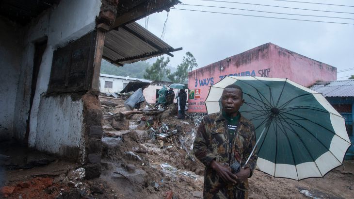 A resident stands with an umbrella in the Chimwankhunda location in Blantyre on March 14, 2023 following heavy rains caused by cyclone Freddy. - The death toll from Cyclone Freddy in Malawi and Mozambique passed 200 on March 14, 2023 after the record-breaking storm triggered floods and landslips in its second strike on Africa in less than three weeks.