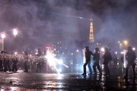 A protester shoots a firework at police officers, with the Eiffel tower seen in the background, during a demonstration on Place de la Concorde in Paris on March 17, 2023, the day after the French government pushed a pensions reform using the article 49.3 of the constitution. - French President's government on March 17, 2023 faced no-confidence motions in parliament and intensified protests after imposing a contentious pension reform without a vote in the lower house. Across France, fresh protests erupted in the latest show of popular opposition to the bill since mid-January. (Photo by JULIEN DE ROSA / AFP)