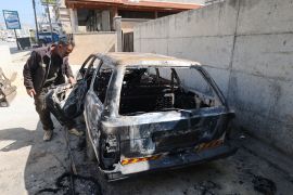 A man looks at a burnt vehicle