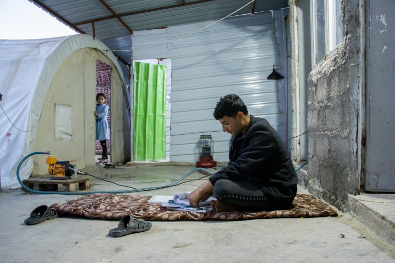A photo of Nazar doing his homework next to his tent.