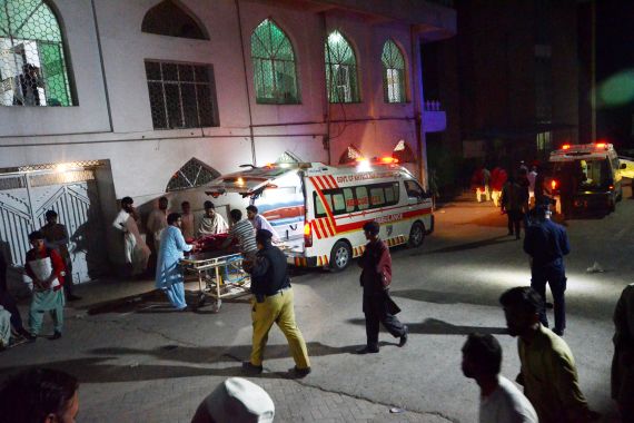 People are seen in a street as an injured citizen is being loaded into an ambulance to be taken to a hospital following a strong earthquake in Peshawar, Pakistan.
