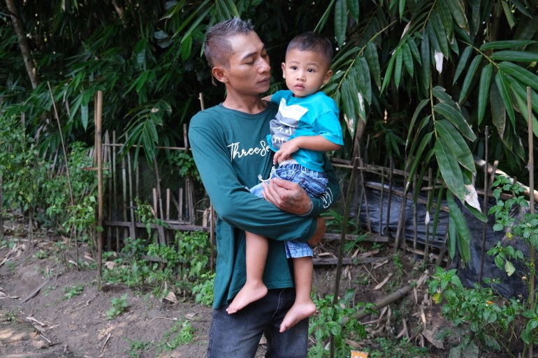 Andik Harianto standing outside holding his two year old son Rian.