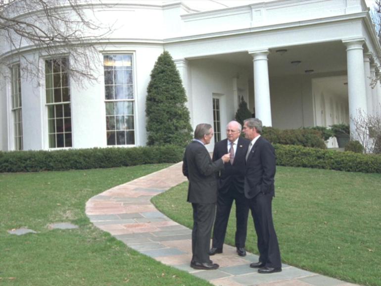 George W Bush with Dick Cheney and Donald Rumsfeld standing on the lawn