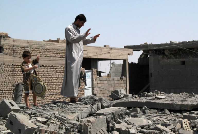 Bilal Hussain Zaidan, right, and his nephew Taha Makki, look for household items on the roof of their partially destroyed house