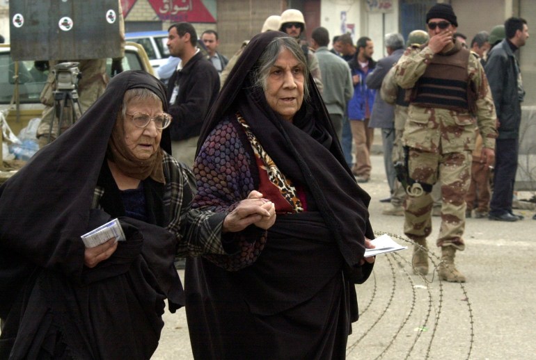 Two elderly Iraqi women comfort each other on their way to a polling station in Baghdad, Iraq, Sunday, Jan 30, 2005 to vote in their country's first free election in a half-century. (AP Photo/Samir Mizban)