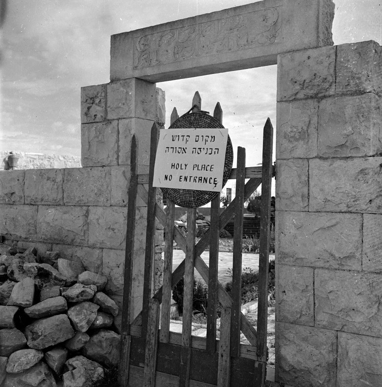 Black and white photo of a sign that reads "Holy place, no entrance" on a gate