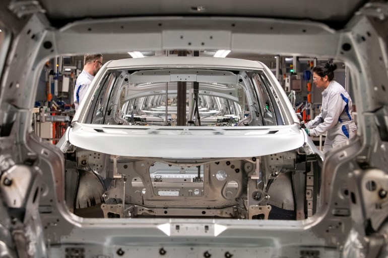 Workers complete an electric car body on the assembly line of the Volkswagen plant in Zwickau, Germany on February 25, 2020.