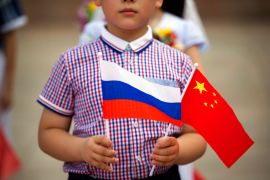 A boy holds Russian and Chinese flags at a welcoming ceremony for Russian President Vladimir Putin at the Great Hall of the People in Beijing in 2016 [File Mark Schiefelbein/AP]