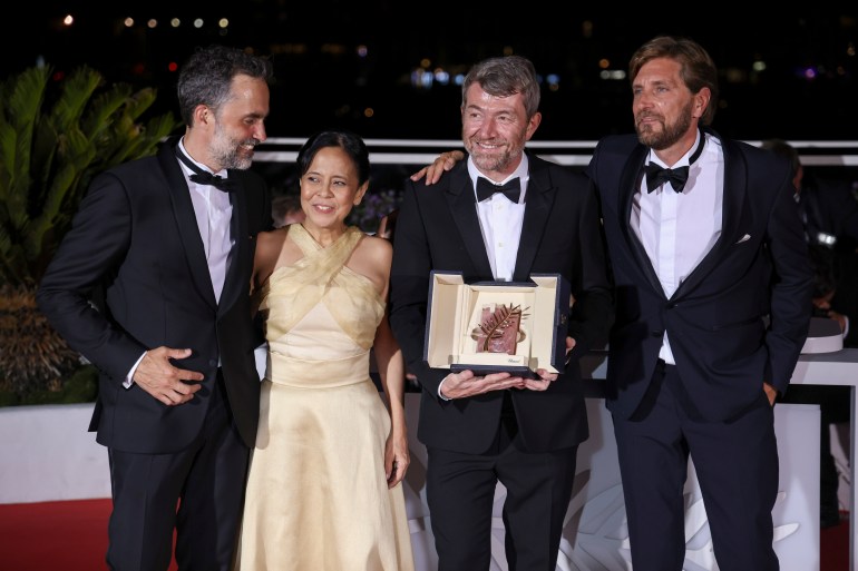 Erik Hemmendorff, from left, Dolly De Leon, Philippe Bobe, director Ruben Ostlund pose with the Palm d'Or Award for "Triangle of Sadness" during the photo call following the awards ceremony at the 75th international film festival, Cannes, southern France, Saturday, May 28, 2022.