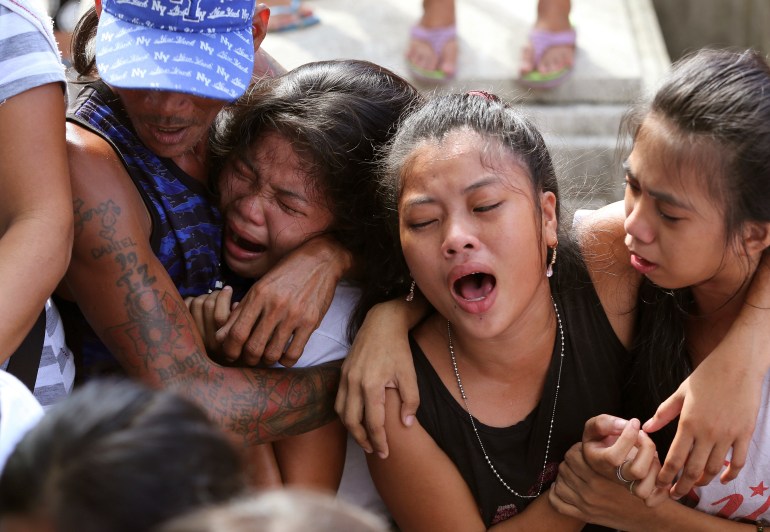 Distraught family and friends hug each other and cry at the funeral of a man killed by police as an alleged drug suspect.