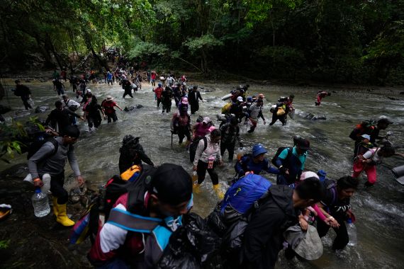 A group of migrants, mostly Venezuelans, cross a river during their journey through the Darien Gap from Colombia into Panama hoping to reach the U.S., Saturday, Oct. 15, 2022. (AP Photo/Fernando Vergara)