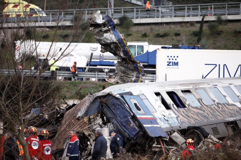 Rescuers stand near debris of trains after a collision in Tempe, about 376 kilometres (235 miles) north of Athens