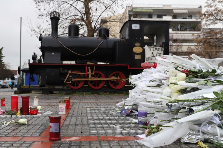 Flowers and candles lie in the memory of the victims of a deadly train crash outside a train station of Larissa city, north of Athens, Greece, Thursday, March 2, 2023. Emergency workers are searching late into the night for survivors and bodies after a passenger train and a freight train crashed head-on in Tempe, central Greece just