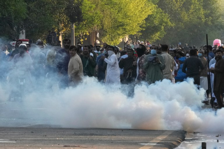 Supporters of Pakistan's former Prime Minister Imran Khan run for cover as police fire tear gas shells.
