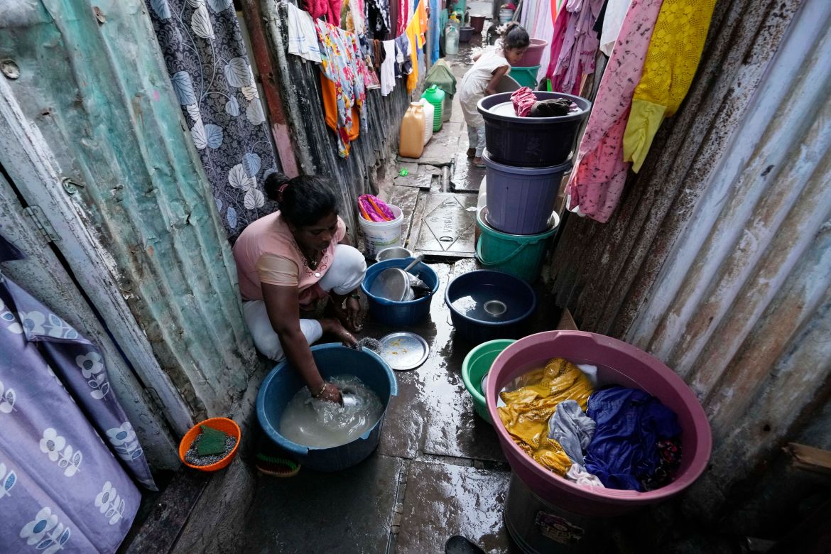 A woman washes utensils outside her house in a slum area on the eve of World Water Day in Mumbai, India