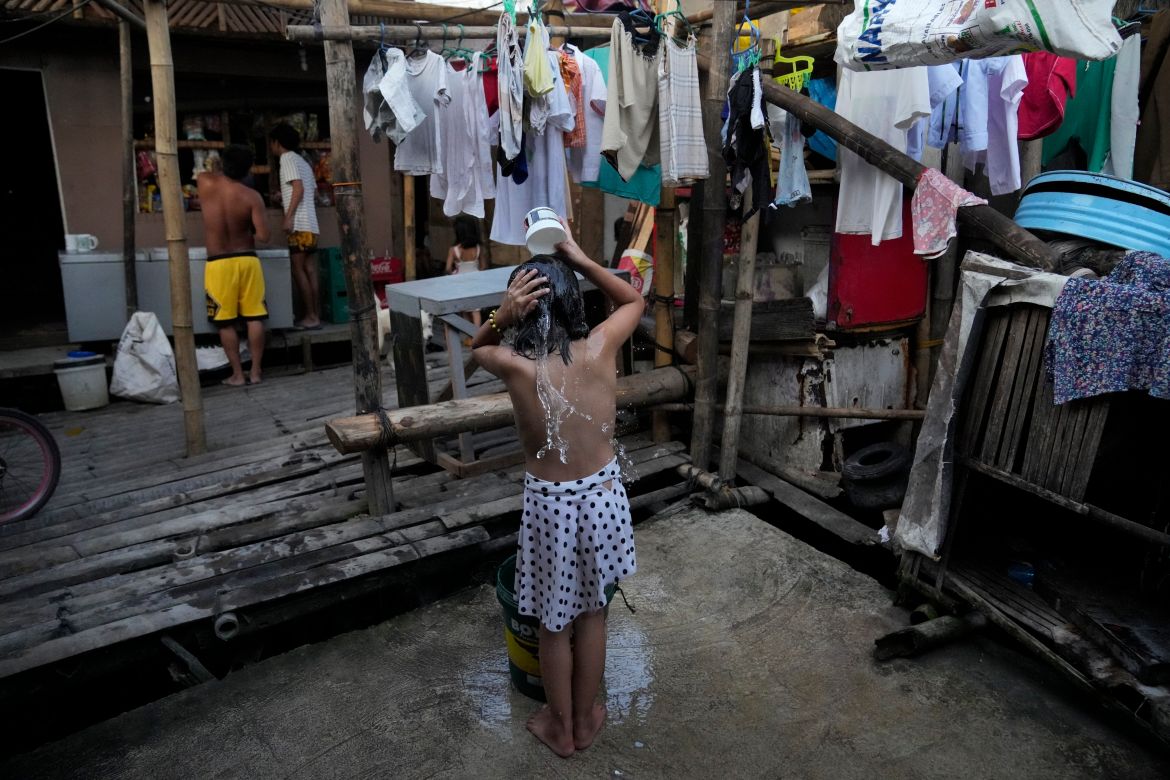 A girl takes a bath near a manual water pump at a slum area in Muntinlupa, Philippines