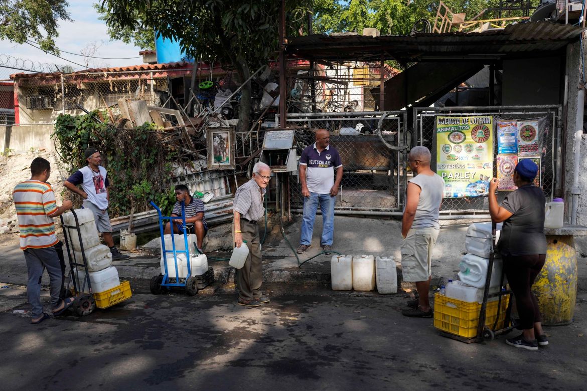Locals wait for their turn to fill their water containers from water collected in an abandoned highway tunnel at the Cotiza neighborhood of Caracas, Venezuela