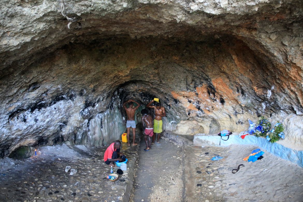 People bathe and do their laundry in a spring inside a cave due to no running water at their home in Port-au-Prince, Haiti