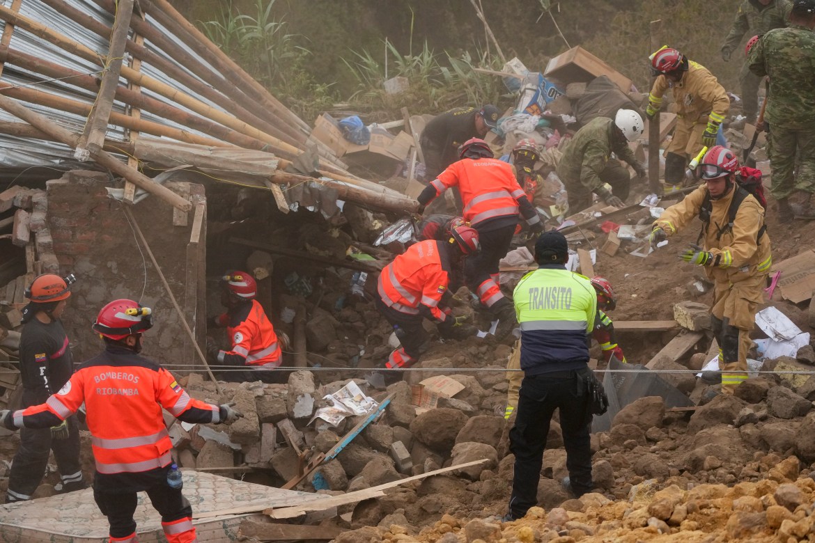 Rescue workers inspect a home destroyed by a deadly landslide that buried dozens of homes in Alausi, Ecuador