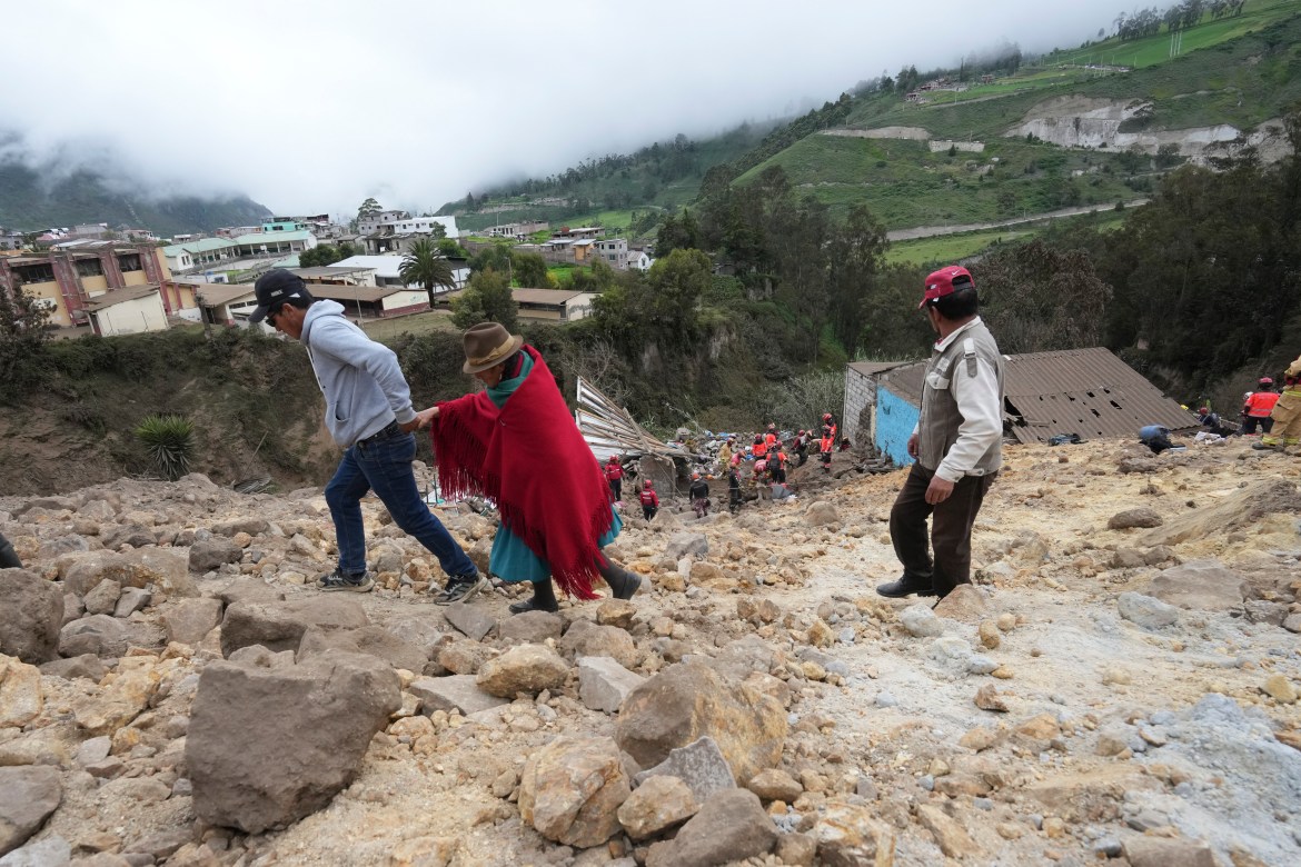 Residents walk on mud and stones after a deadly landslide buried dozens of homes in Alausi, Ecuador