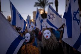 Demonstrators wear masks and wave Israeli flags during a protest