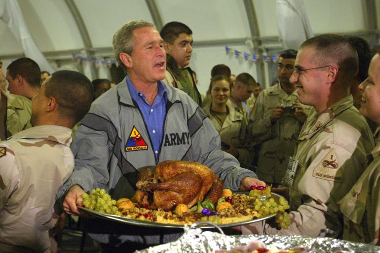 George W Bush with a platter of turkey and fixings as he visits US troops in Baghdad for Thanksgiving