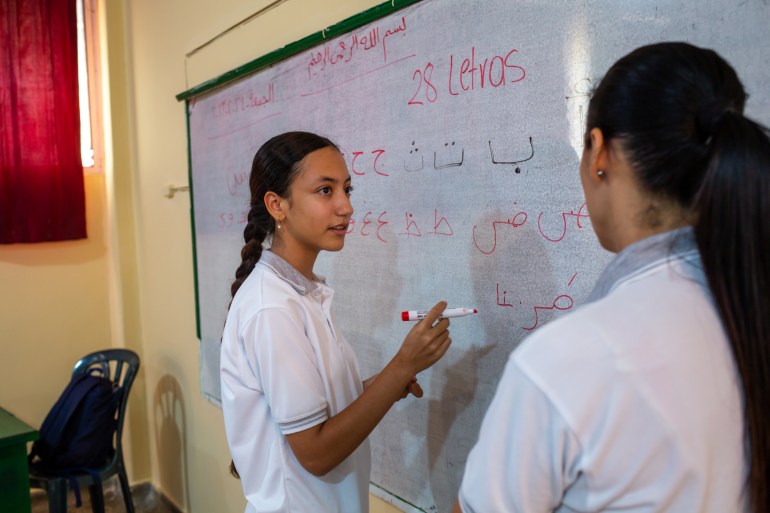Two students write on a white board at the Dar El Arkham school