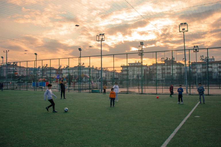 Kids play football on an outdoor pitch.