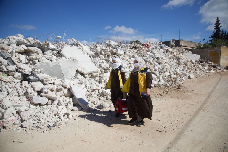 Shahd and her colleague carry their medical bag through rubble to provide free medical care to survivors of the earthquakes